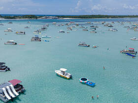 A vibrant scene at a popular sandbar, featuring numerous boats and people enjoying water activities — perfect for a fun day on the water.