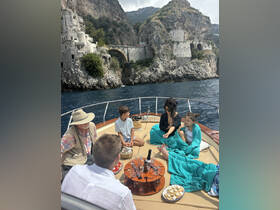 A family enjoys a delightful afternoon on a boat, sharing snacks and drinks while surrounded by stunning coastal scenery — perfect for memorable gatherings on the water.