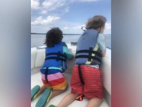 Two children in life jackets enjoy the view from a boat, embodying the spirit of adventure on the water. Perfect for family outings and creating lasting memories.
