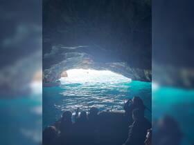 A group of adventurers enjoys a boat ride through a stunning cave, capturing the breathtaking view of the turquoise waters beyond — a perfect moment for exploration and discovery.