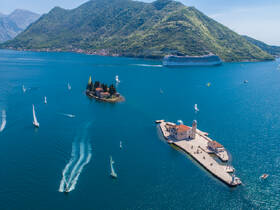 A stunning aerial view of a picturesque island with a church, surrounded by sailboats and the breathtaking coastline — a perfect representation of a sailing adventure in a scenic destination.