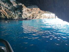 A group of swimmers enjoys exploring a stunning cave, surrounded by crystal-clear waters — a perfect adventure for snorkeling enthusiasts.