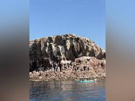 A scenic view featuring a small boat near a stunning rocky coastline, showcasing the beauty of the landscape and the joy of exploring nature by water.