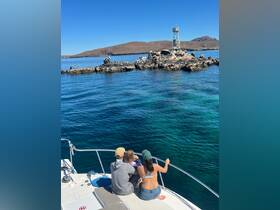 A family enjoys a scenic view from their boat, gazing at a rocky landmark in the ocean — a perfect moment for exploration and adventure on the water.