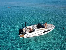 A couple enjoys a refreshing swim in crystal-clear waters while a sleek boat is anchored nearby, capturing the essence of a perfect day on the water.