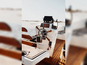 A detailed view of the helm and console area inside a boat, showcasing the steering wheel and modern navigation equipment — ideal for those looking to explore the waters.