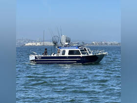A fishing boat named 'Raider' is underway in the water, showcasing its sleek design and fishing gear, perfect for sport fishing adventures.