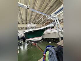 A green boat is prominently displayed in a storage facility, showcasing its sleek design and structure, with crew members visible in the background.