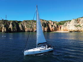 A stunning aerial view of a sailboat navigating through clear waters, with dramatic cliffs in the background, perfect for showcasing sailing adventures along the coast.