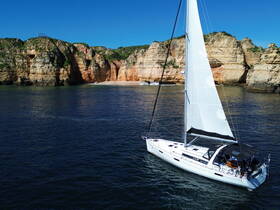 A stunning aerial view of a sailboat navigating near dramatic cliffs, showcasing the beauty of coastal sailing adventures.
