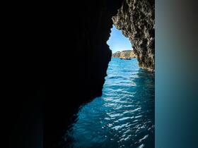 A stunning view from inside a cave looking out to the ocean, with a boat visible in the distance — a perfect representation of coastal adventures and exploration.