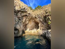 A stunning view of a rocky cave along the coastline, showcasing the natural beauty of the area — perfect for exploring hidden gems during boat trips.