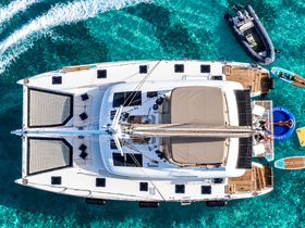 A stunning aerial view of a catamaran cruising through crystal-clear waters, showcasing its spacious deck and luxurious amenities.