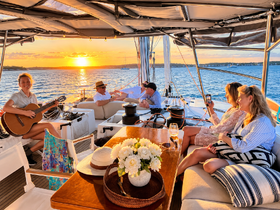 A lively group enjoys a sunset gathering on a yacht, with music and drinks creating a perfect atmosphere for celebration and relaxation on the water.