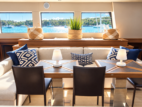 A beautifully designed interior of a boat featuring a cozy seating area and dining table, perfect for relaxing and enjoying the scenic views through large windows.