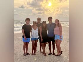 A joyful group poses together on the beach at sunset, capturing a memorable moment of family fun and celebration by the water.