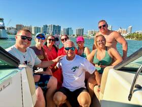 A lively group of friends enjoys a fun day on the boat, capturing memories against a vibrant waterfront backdrop — perfect for summer adventures.