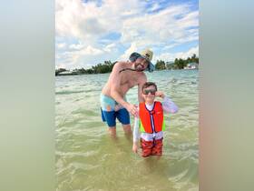 A joyful moment captured as a father and son enjoy swimming together in shallow waters, showcasing the fun of family beach outings.