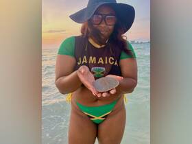 A woman holds a stingray while enjoying a beautiful sunset at the beach, showcasing a unique wildlife encounter in Jamaica.