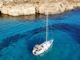 A stunning aerial view of a sailboat navigating through crystal-clear turquoise waters, showcasing the beauty of the coastline and perfect for sailing adventures.