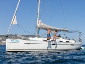 Two friends joyfully jump off the side of the 'Blue Magic' sailboat into the sparkling waters, capturing the essence of summer fun and adventure on the sea.