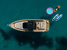 Aerial view of a stylish boat surrounded by water toys including jet skis and paddleboards, perfect for a fun day on the water.