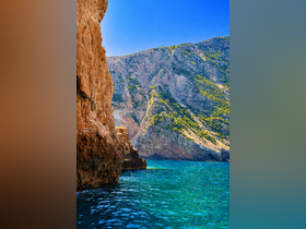 Breathtaking view of rugged cliffs meeting crystal-clear turquoise waters, showcasing the stunning natural beauty of the coastline.