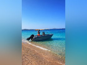 A person stands on a boat near the beach, enjoying the clear waters on a sunny day — perfect for summer adventures and water activities.