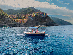 A scenic view of a boat cruising near the colorful coastal village of Cinque Terre, showcasing the stunning landscape and vibrant architecture.