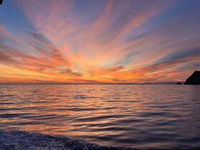 A breathtaking sunset paints the sky with vibrant colors over the tranquil ocean, creating a perfect backdrop for memorable boating experiences.