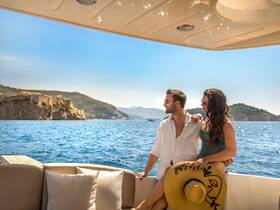 A couple enjoys a sunny day on a boat, admiring the stunning coastal scenery — perfect for romantic getaways and scenic cruises.