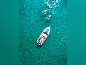 An aerial view captures a yacht anchored in crystal-clear waters, with two kayakers enjoying the vibrant surroundings — a perfect scene for water sports and adventure.
