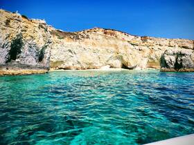 A serene view of a swimmer enjoying the crystal-clear waters near stunning coastal cliffs — a perfect spot for relaxation and exploration.