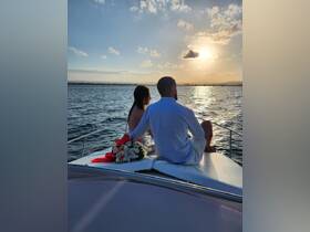 A couple enjoys a romantic sunset on a boat, creating a perfect backdrop for special celebrations or intimate moments on the water.