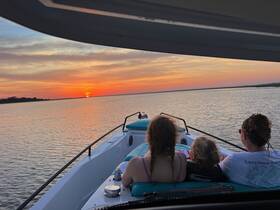 A family enjoys a serene sunset view from their boat, creating a perfect moment for relaxation and connection on the water.