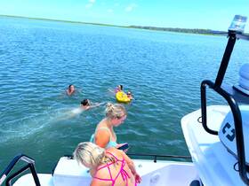 A lively group enjoys a fun day in the water, swimming and playing with a yellow float, showcasing the perfect summer boating experience.