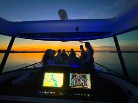 A group of friends enjoys a sunset cruise aboard a boat, creating a perfect backdrop for memorable moments on the water.