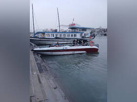 A speedboat is docked alongside a larger vessel, showcasing the vibrant marine scene at the harbor.