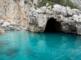 A stunning view of a coastal cave surrounded by turquoise waters, showcasing the natural beauty of the landscape — perfect for exploring hidden gems on your boating adventures.