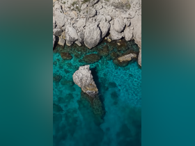 Aerial view of rocky coastline and clear turquoise waters, showcasing the natural beauty of the area.