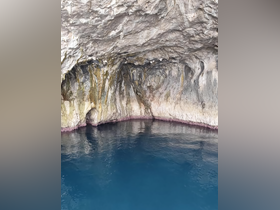 A stunning view of a coastal cave reflecting in the clear blue waters, showcasing the natural beauty of the area — perfect for eco tours and scenic boat trips.