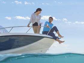 A couple enjoys a sunny day on a boat, smiling and relaxing by the water — perfect for romantic getaways or day trips on the ocean.