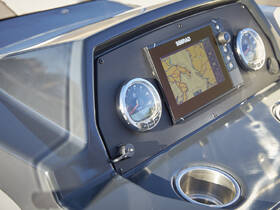 Close-up view of a boat's helm featuring a modern SIMRAD display and gauges, showcasing the sleek design and functionality of the vessel's interior.