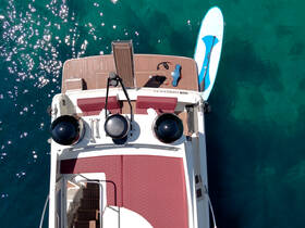 An aerial view of a boat's deck featuring a paddleboard and seating area, perfect for enjoying water activities and relaxation on the open sea.