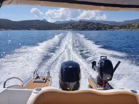 A stunning view from the back of a boat underway, showcasing the powerful outboard motors and the beautiful blue waters, perfect for a day of adventure on the sea.