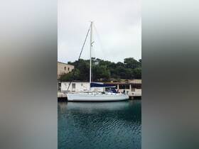 A sleek sailboat docked at a serene harbor, surrounded by lush greenery — an ideal spot for sailing adventures.