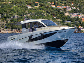 A sleek speedboat navigates through clear waters, showcasing its elegant design and performance against a scenic backdrop of lush greenery.
