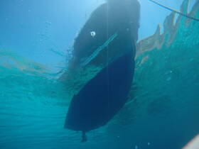 An underwater view of a boat, showcasing its hull against the vibrant blue waters — a unique perspective for marine enthusiasts.
