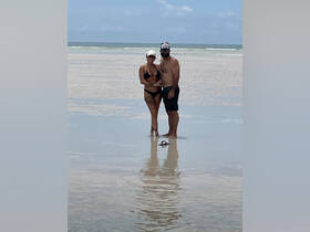 A couple enjoys a romantic moment on the beach, standing in shallow water with reflections creating a picturesque scene — perfect for snorkeling adventures.