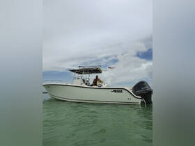 A Mako boat cruising through clear waters with a man at the helm, showcasing a perfect day on the water.